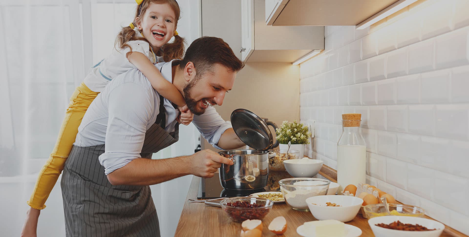 A parent and child cooking together in a bright home kitchen